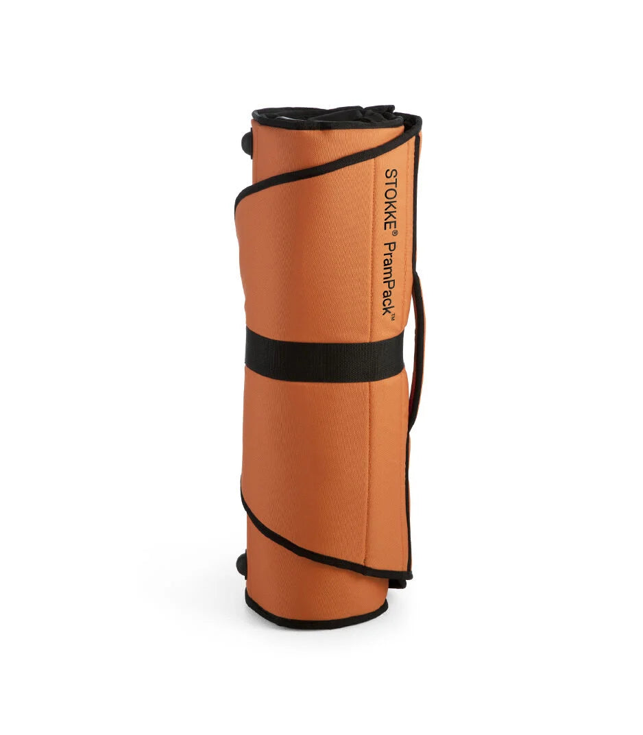 Pystyyn rullattu oranssi Stokke PramPack -kuljetuslaukku tiiviissä paketissa säilytystä varten.